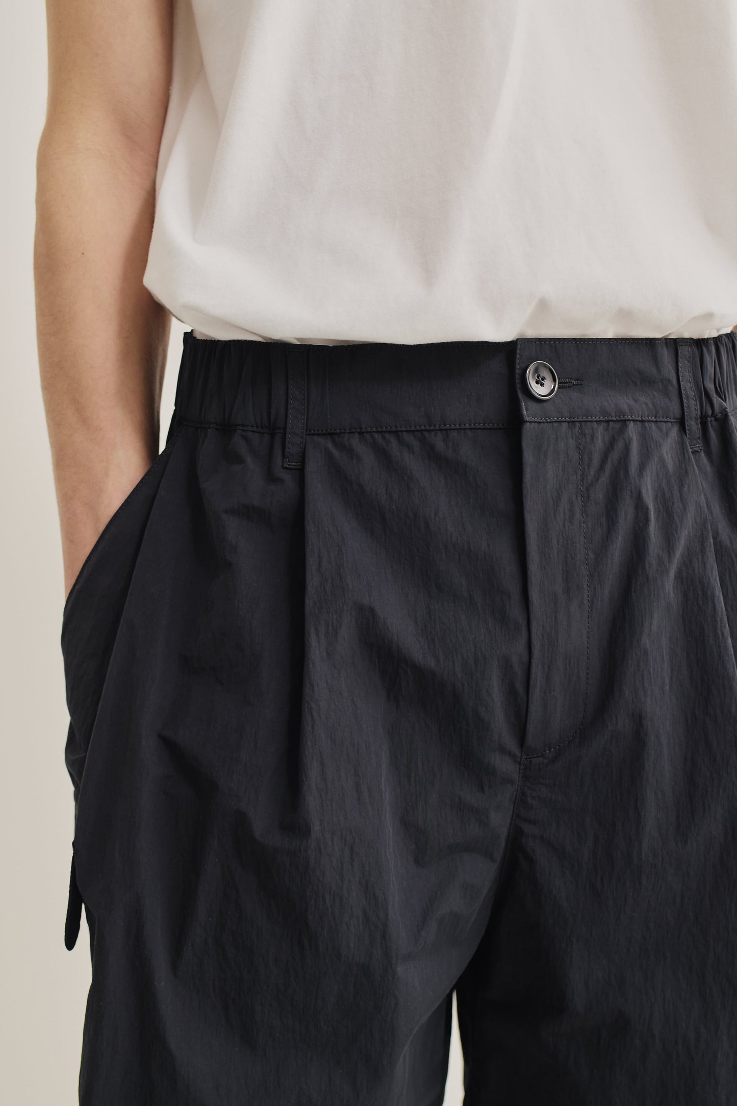 Men's shorts, recycled nylon cotton blend, black, with elastic waist, front pleats, and button closure.