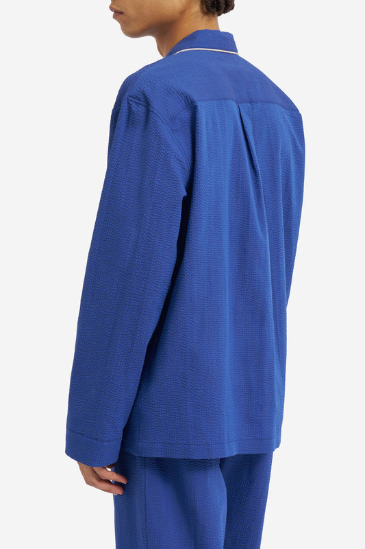Men's long-sleeved shirt and pants pyjama set in blue hour organic cotton seersucker with piped trim.