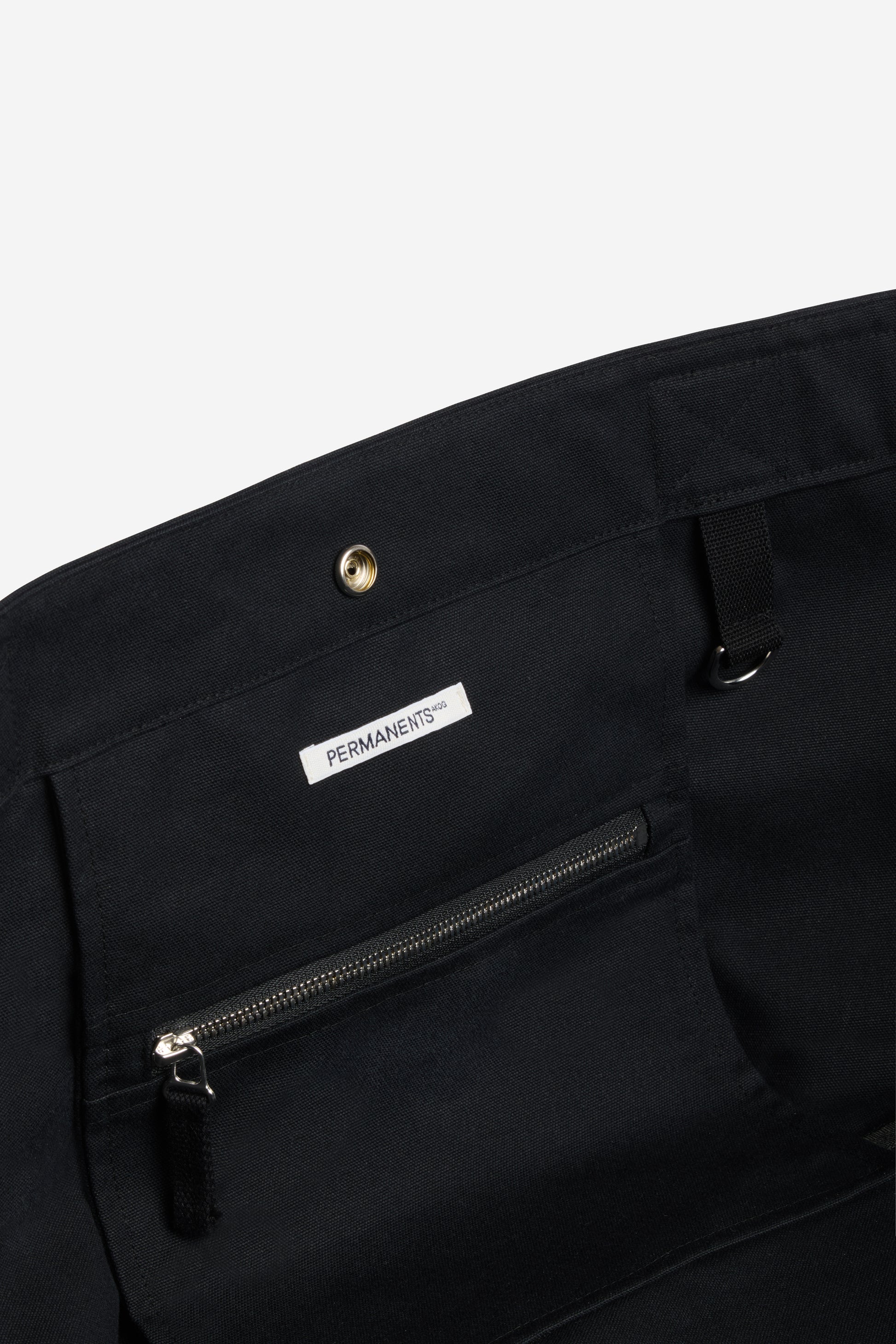 Accessories carryall bag, black recycled Ventile cotton, with interior zip pocket and "PERMANENTS" label.
