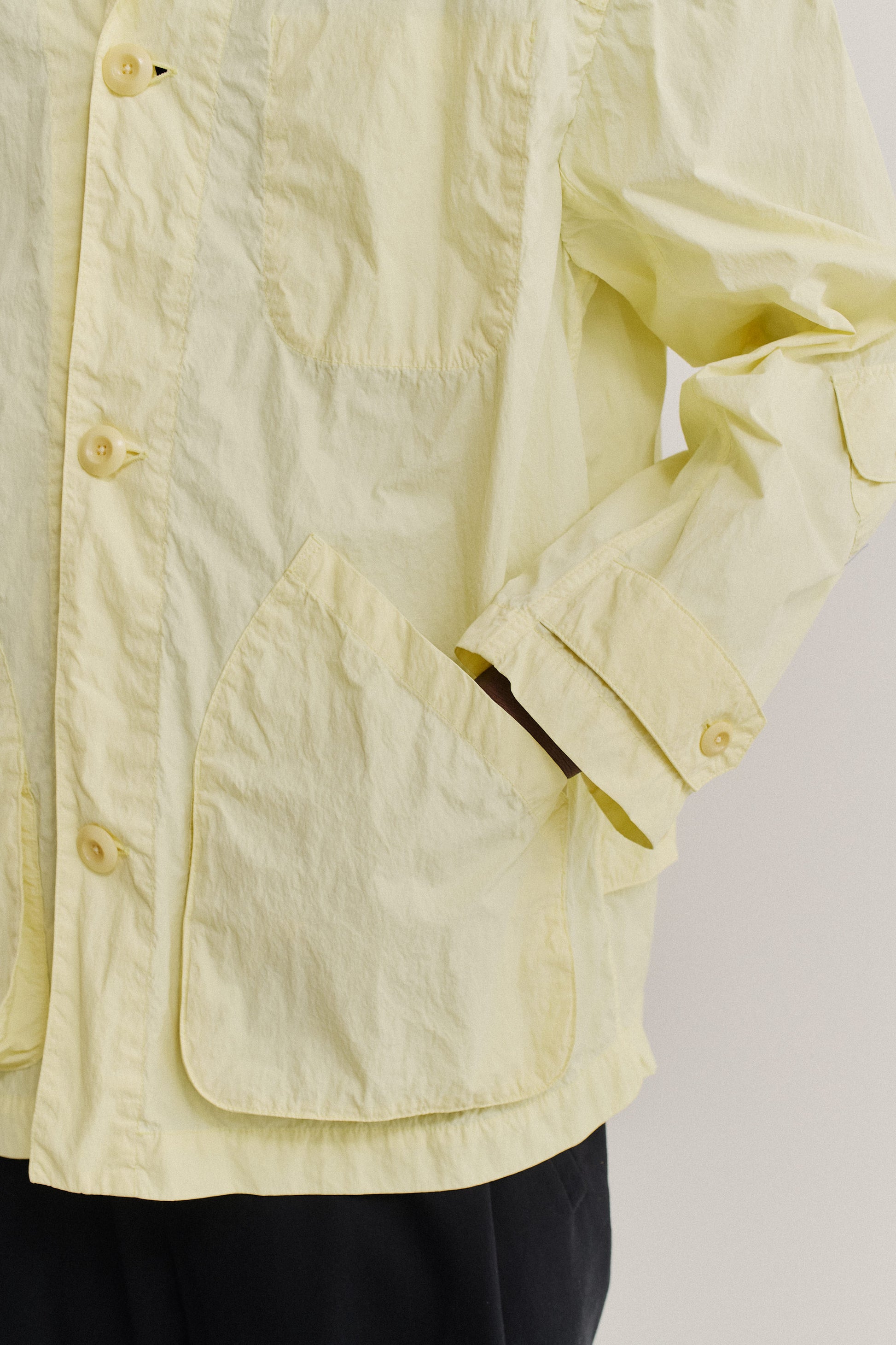 Men's outerwear jacket, recycled polyamide, garment-dyed washed light yellow, with patch pockets and corozo buttons.