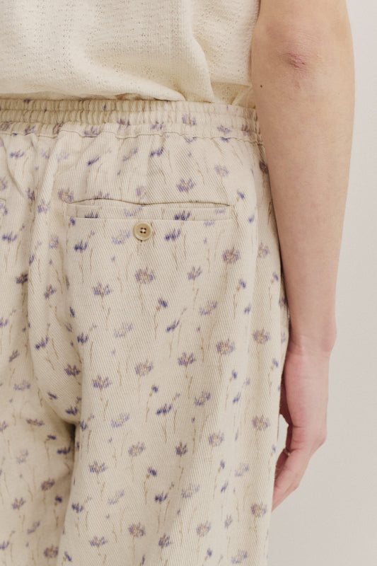 Men's long-pants, cotton-linen blend twill, ecru with subtle lilac floral print, elastic waist, welt pocket.
