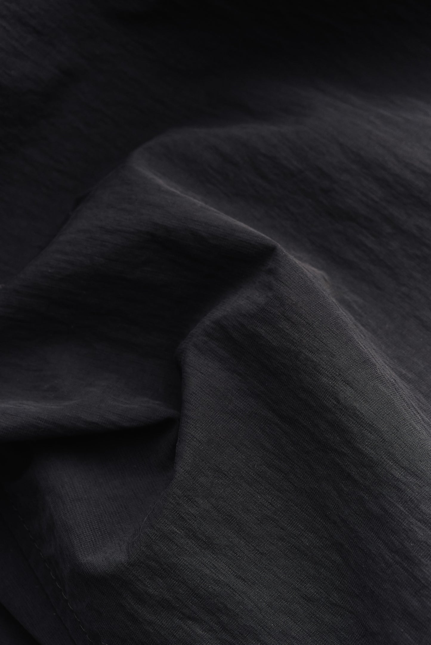 Men's outerwear, black recycled nylon and cotton blend, water-repellent fabric with subtle texture.