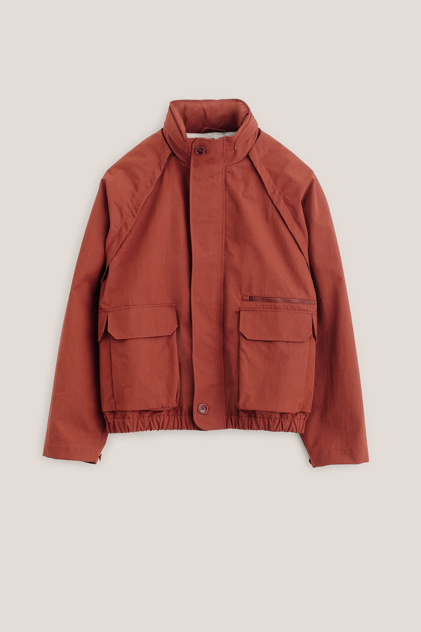 Men's outerwear jacket, cotton blend, water-repellent, rust red, with raglan sleeves and bellows pockets.