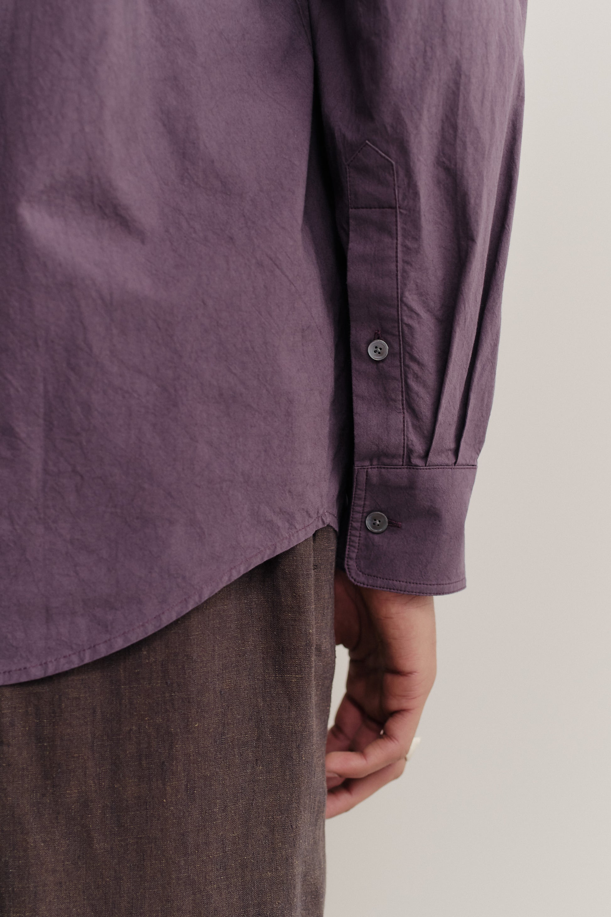 Men's long-sleeved shirt, cotton, subtly grainy, purple, with adjustable cuffs and curved hem.