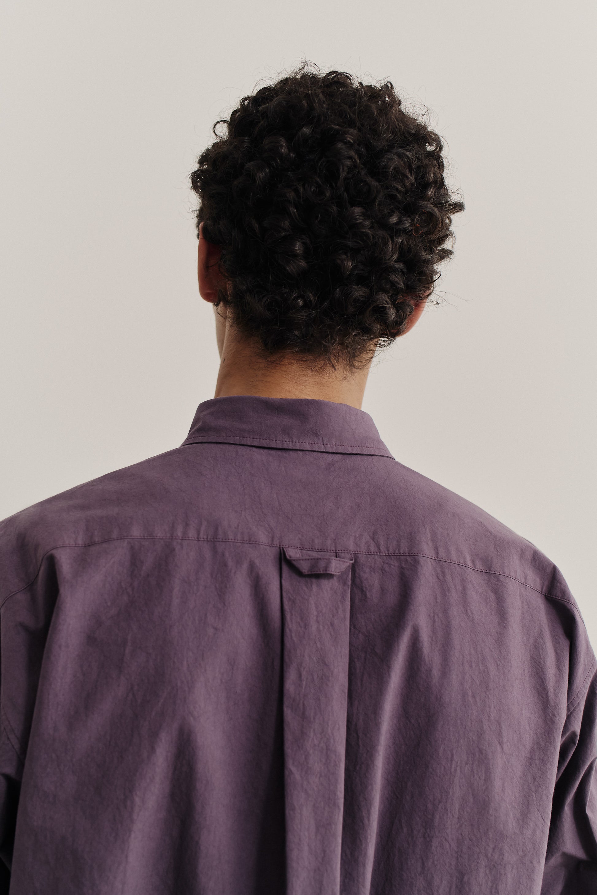 Men's long-sleeved shirt, cotton, smooth yet subtly grainy, purple, oversized, curved hem, patch pocket.