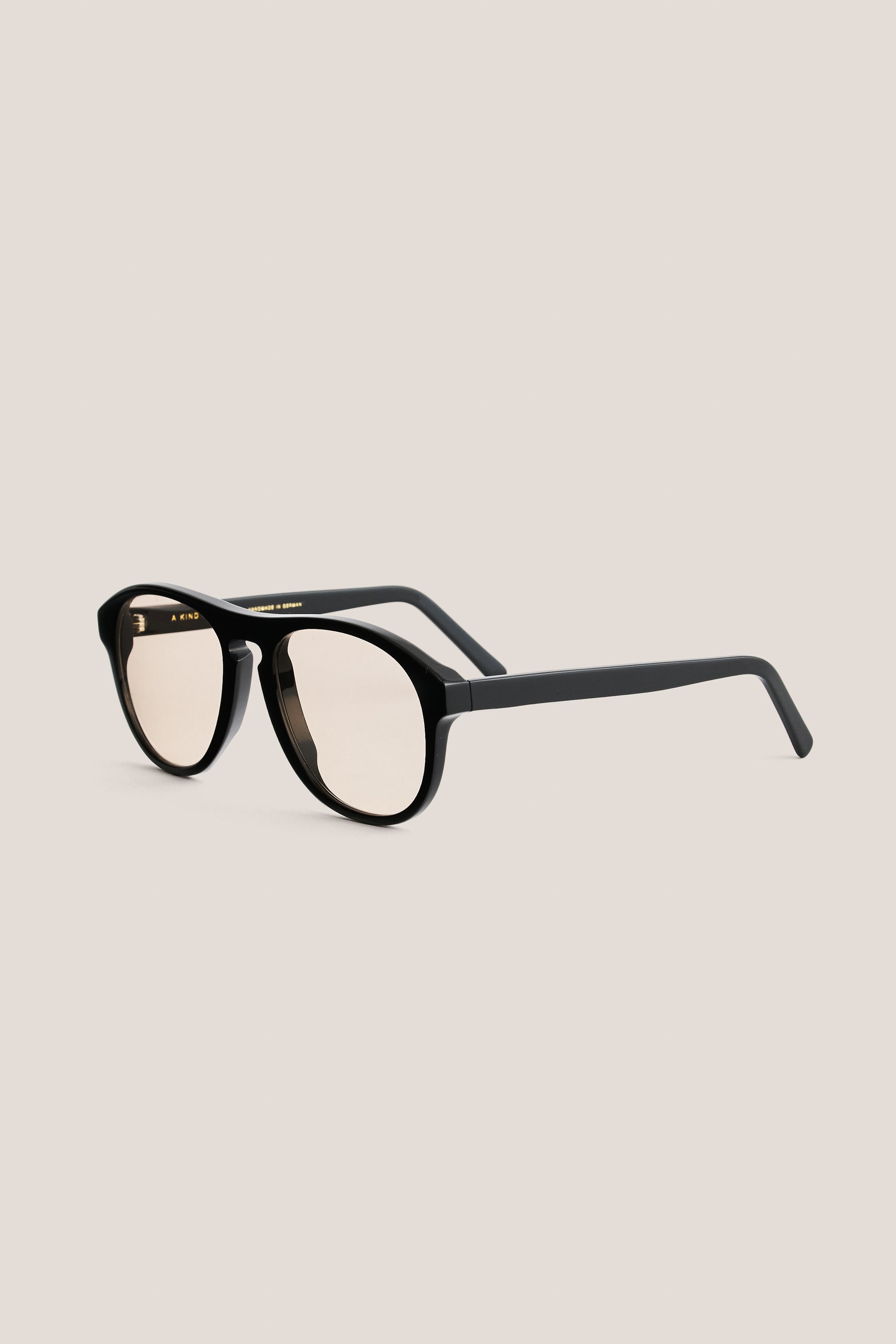 Unisex accessories sunglasses, black acetate aviator-shaped frames with rounded edges and light peach Carl Zeiss® lenses.