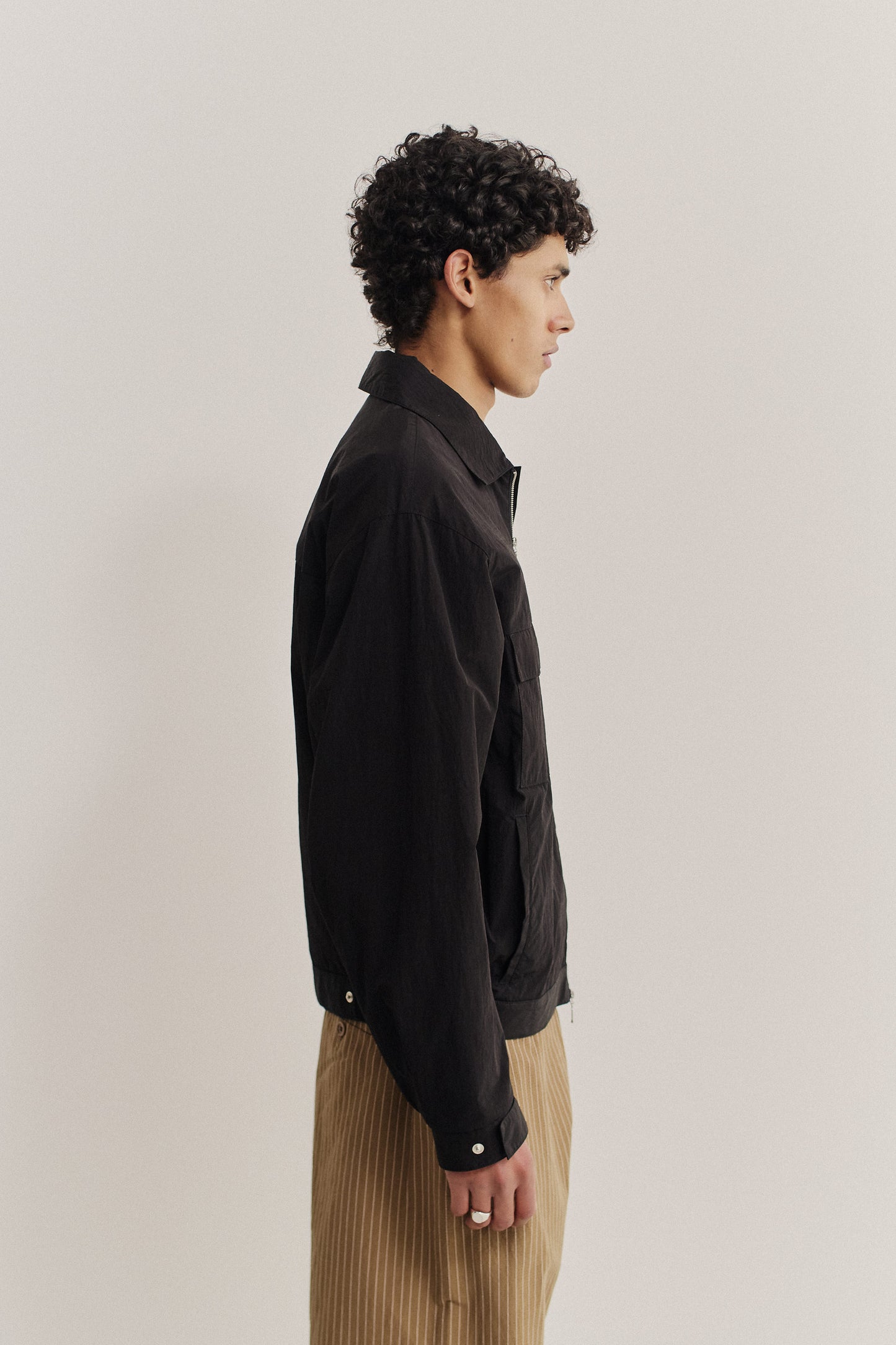 Men's outerwear jacket, black recycled nylon cotton blend, boxy silhouette, flap chest pockets, elasticated waist.
