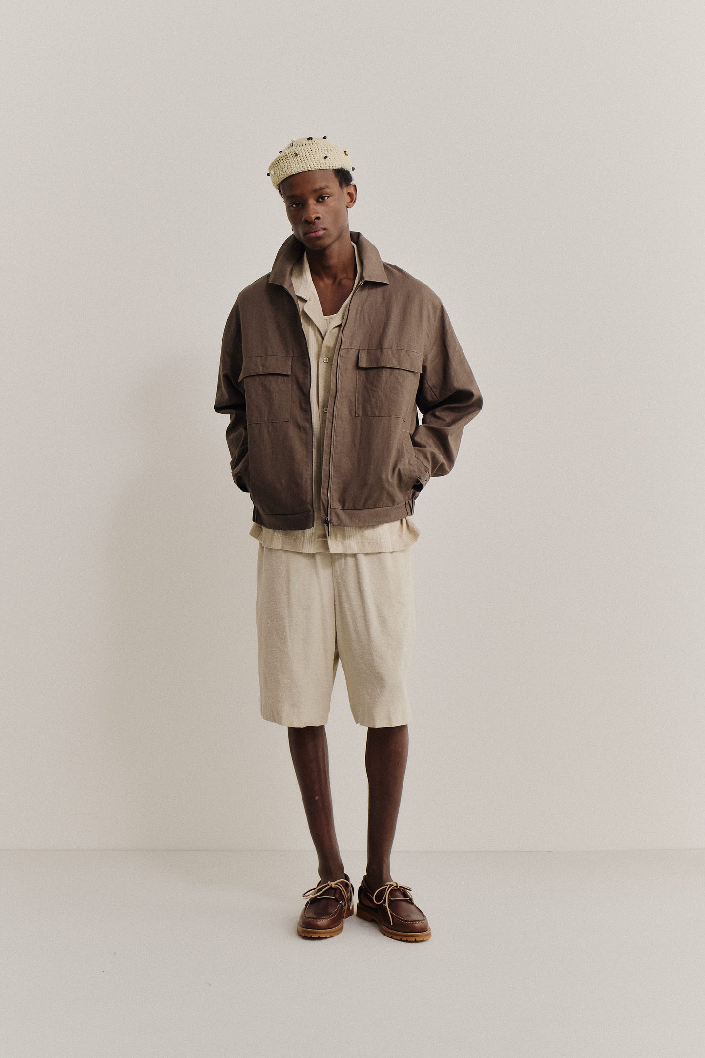 Men's outerwear jacket, brown linen, vintage-inspired with flap chest pockets, elasticated waist, and front zip.