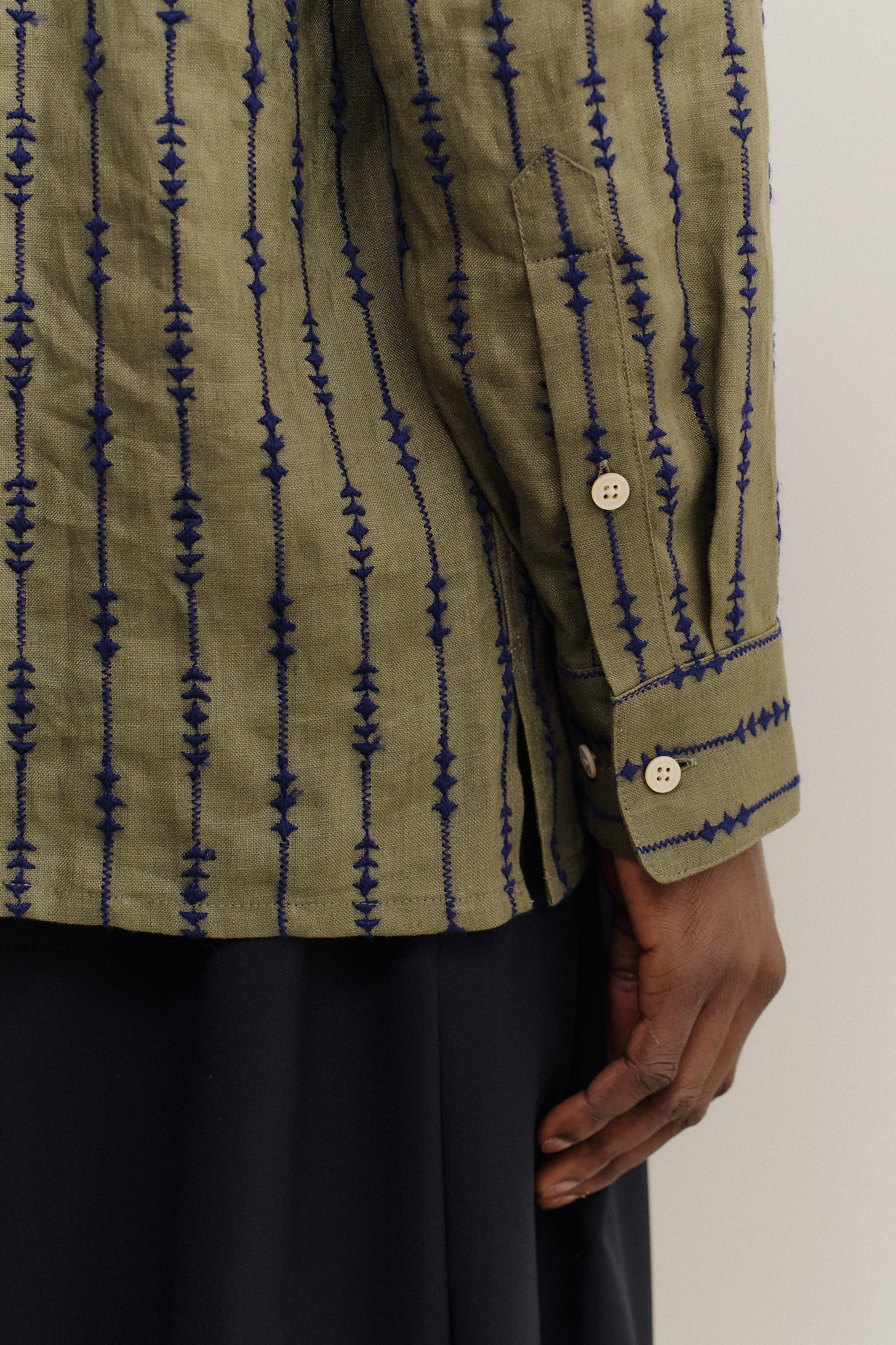 Men's long-sleeved shirt, linen, olive green with navy embroidered vertical patterns, white buttons.