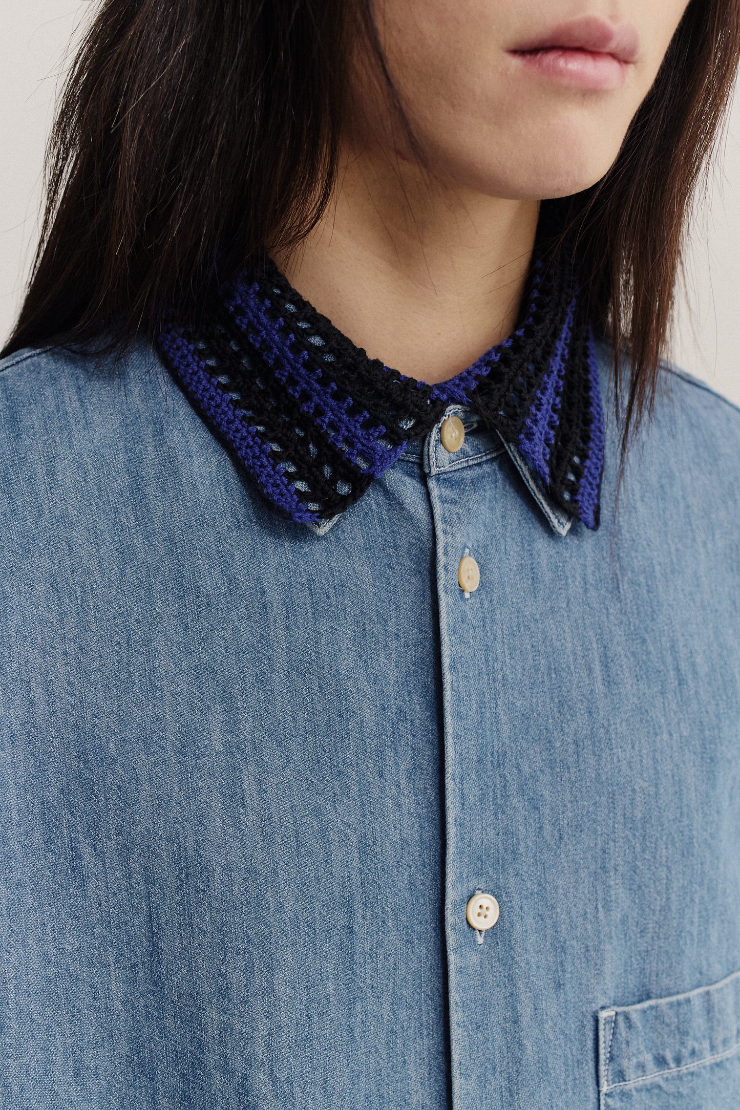 Women's accessory, hand-crocheted Kikoy Collar in navy and black merino wool, worn over a blue denim shirt.