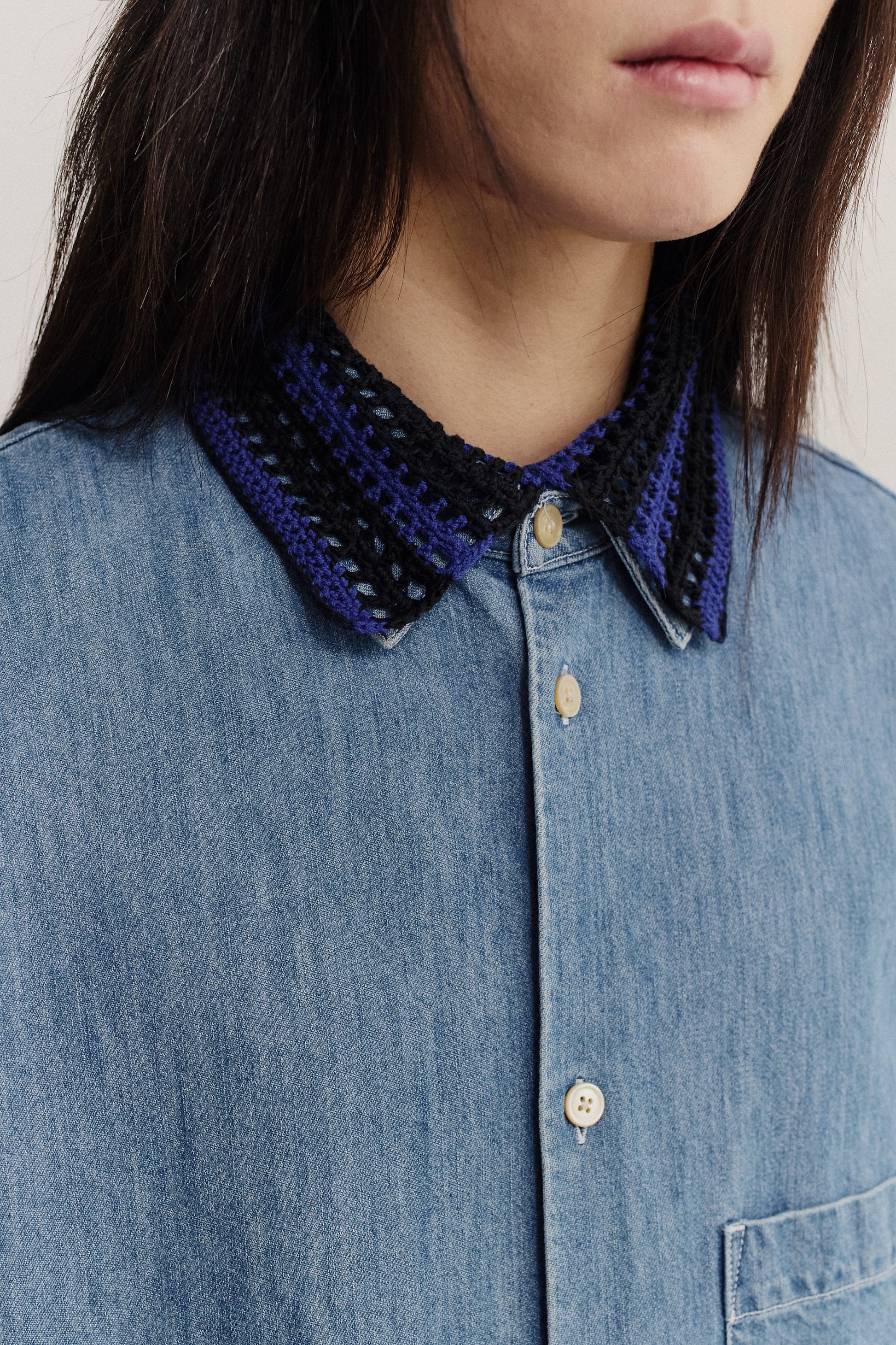Women's accessory, hand-crocheted Kikoy Collar in navy and black merino wool, worn over a blue denim shirt.