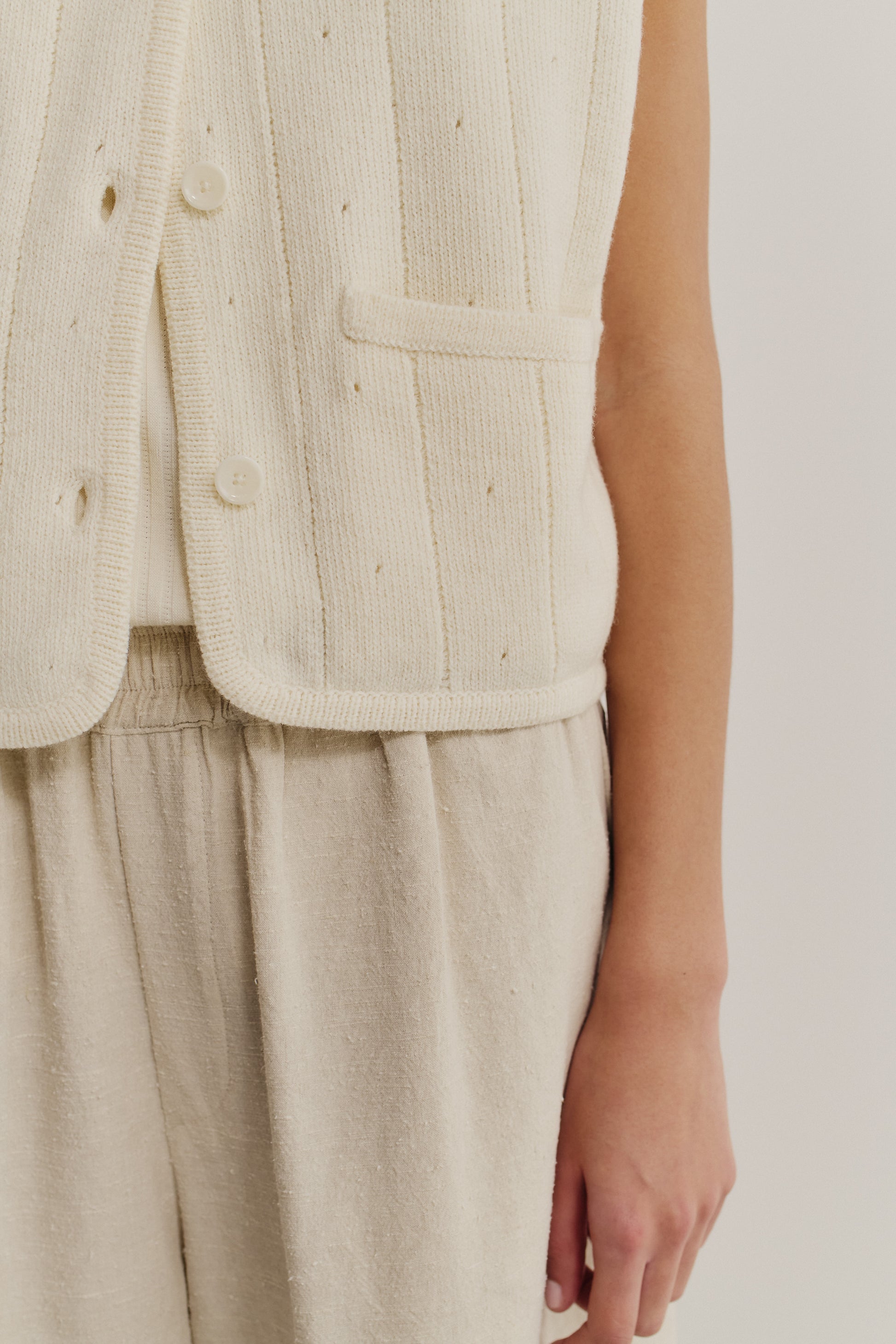 Women's knit vest, 100% merino wool, ajour knit, off-white, with buttons and pocket detail.
