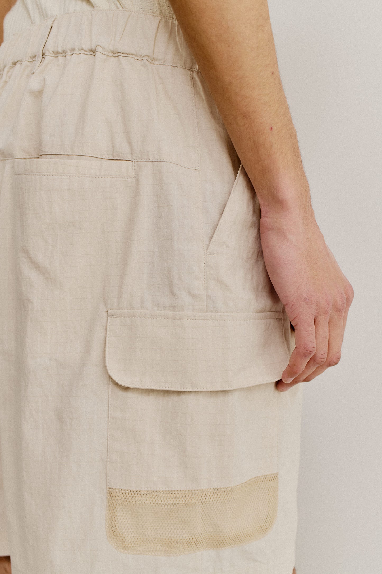 Men's shorts, cotton blend ripstop, waxed finish, beige, with elastic waist, front pleat, slanted pockets, and mesh patch pockets.