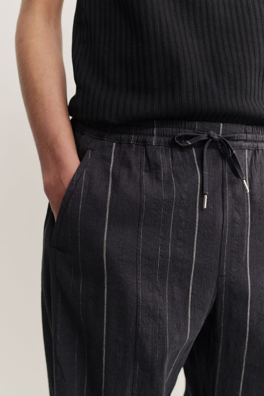 Men's long-pants, cotton-linen blend, black with white stripes, elasticated waistband, and front welt pockets.