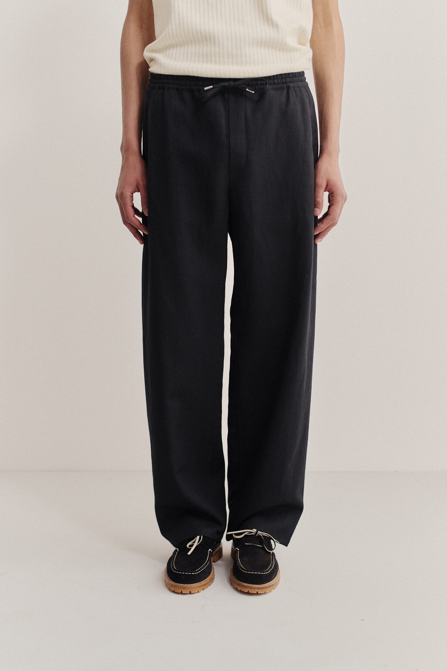 Men's long pants, black worsted wool and linen blend, wide straight fit, elasticated waist, and welt pockets.