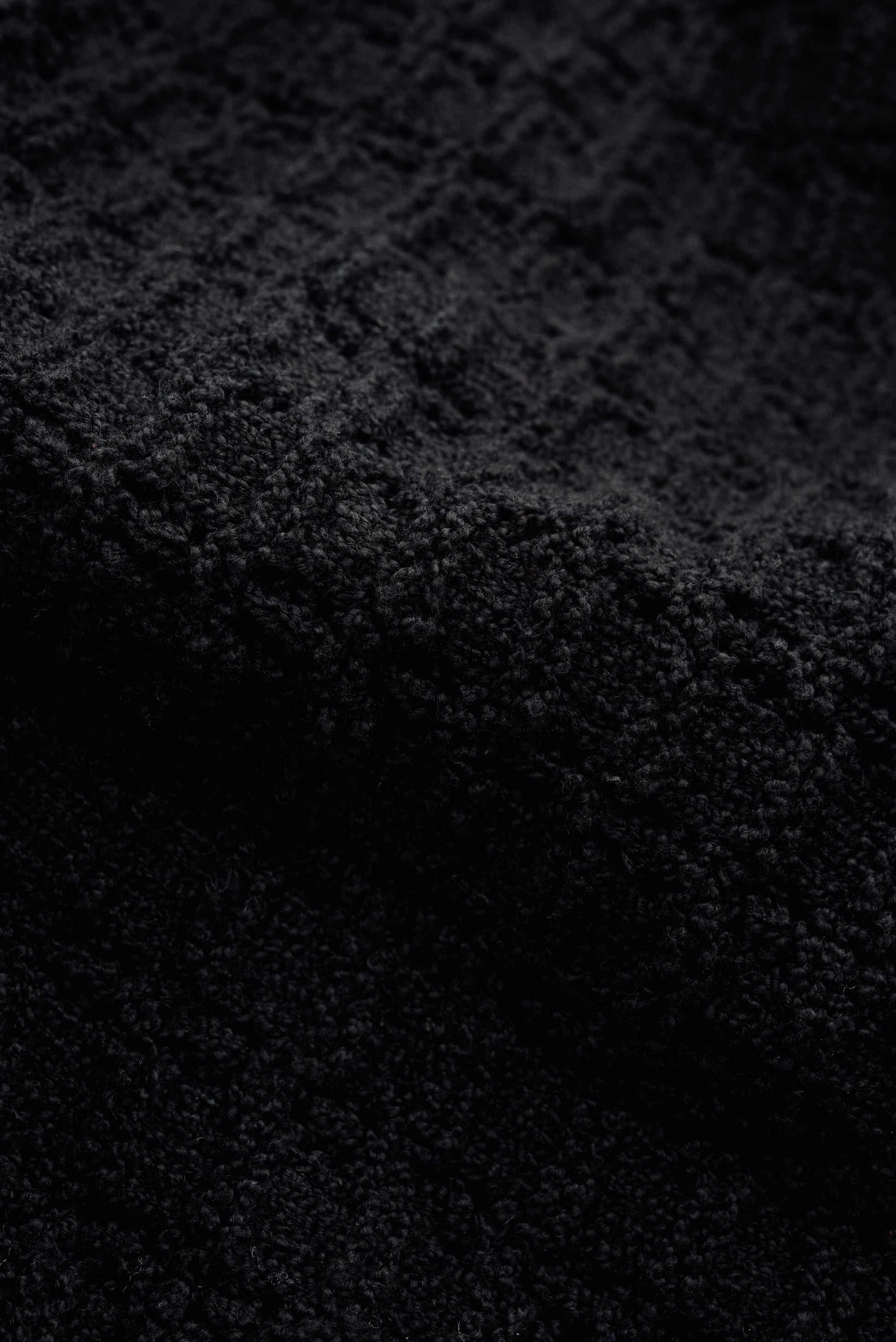 Men's knit vest, black organic cotton-wool bouclé with openwork knit pattern, tactile surface.