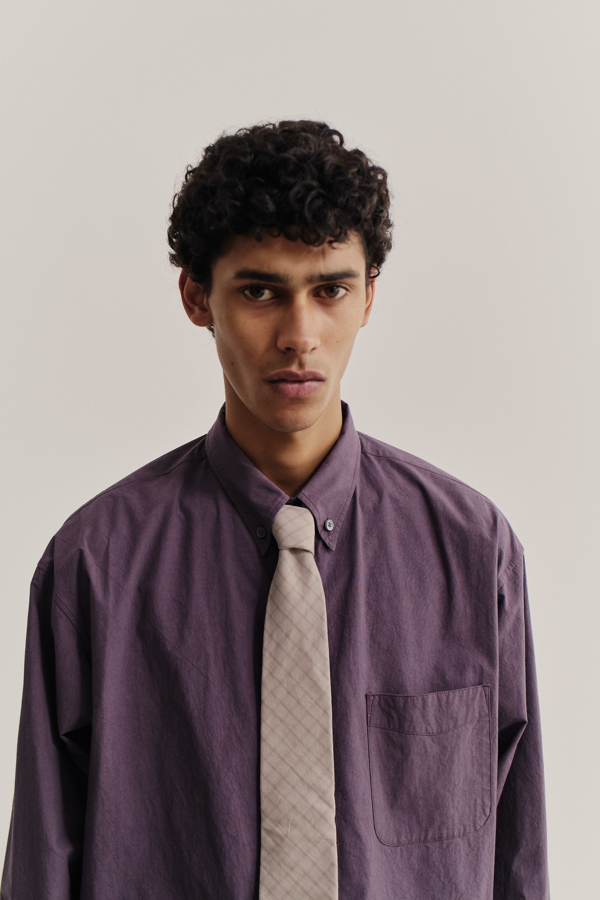 Men's accessories cotton tie, light grey with dark grey squared check pattern, worn with a purple shirt.