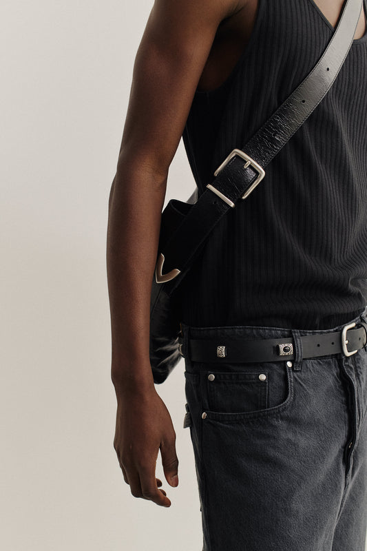 Men's accessories, black LWG-Certified calf leather messenger bag with adjustable belt buckle strap, worn crossbody.