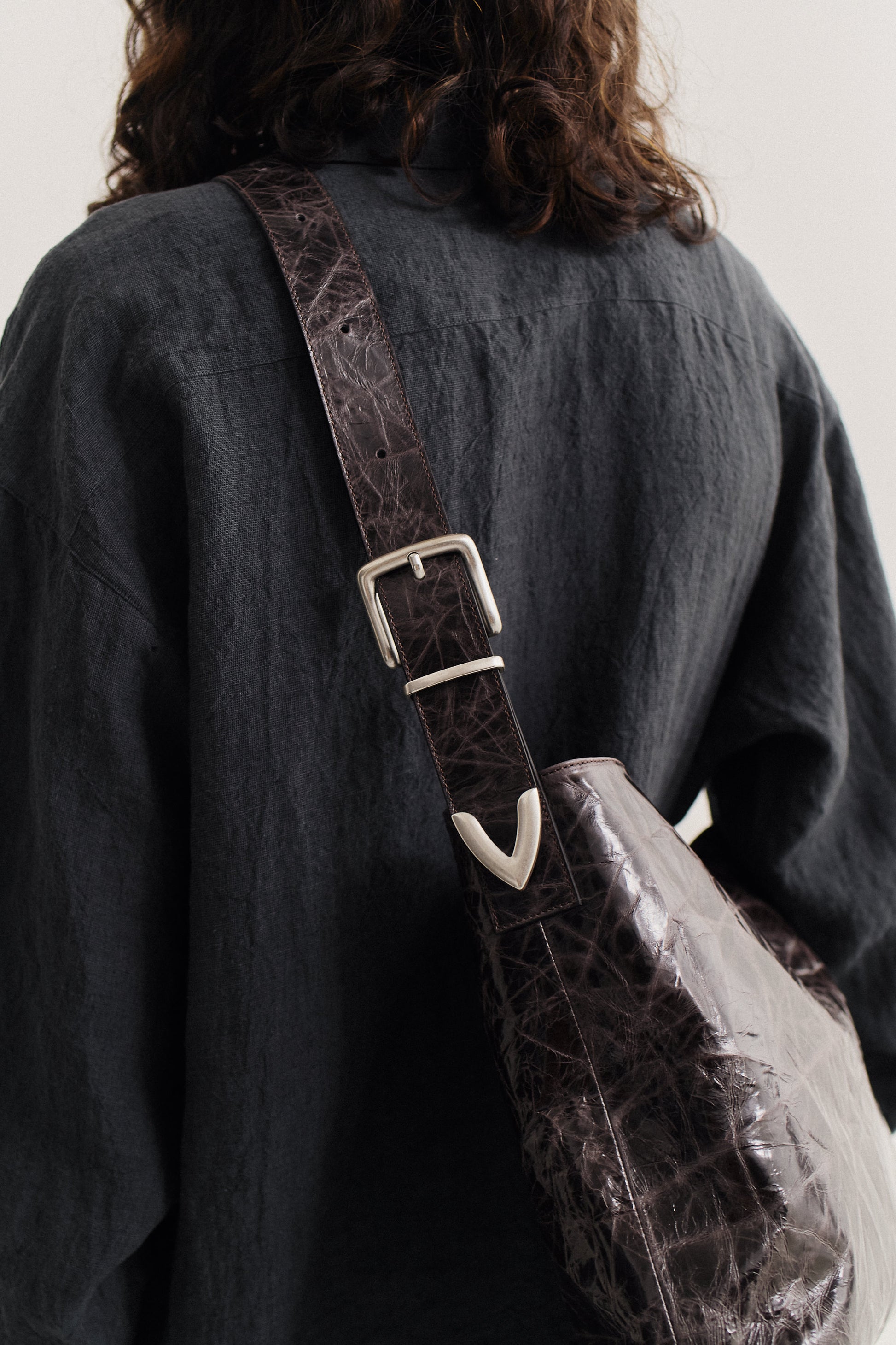 Unisex accessories messenger bag, LWG-certified calf leather, naturally creased, glossy dark brown with silver buckle.