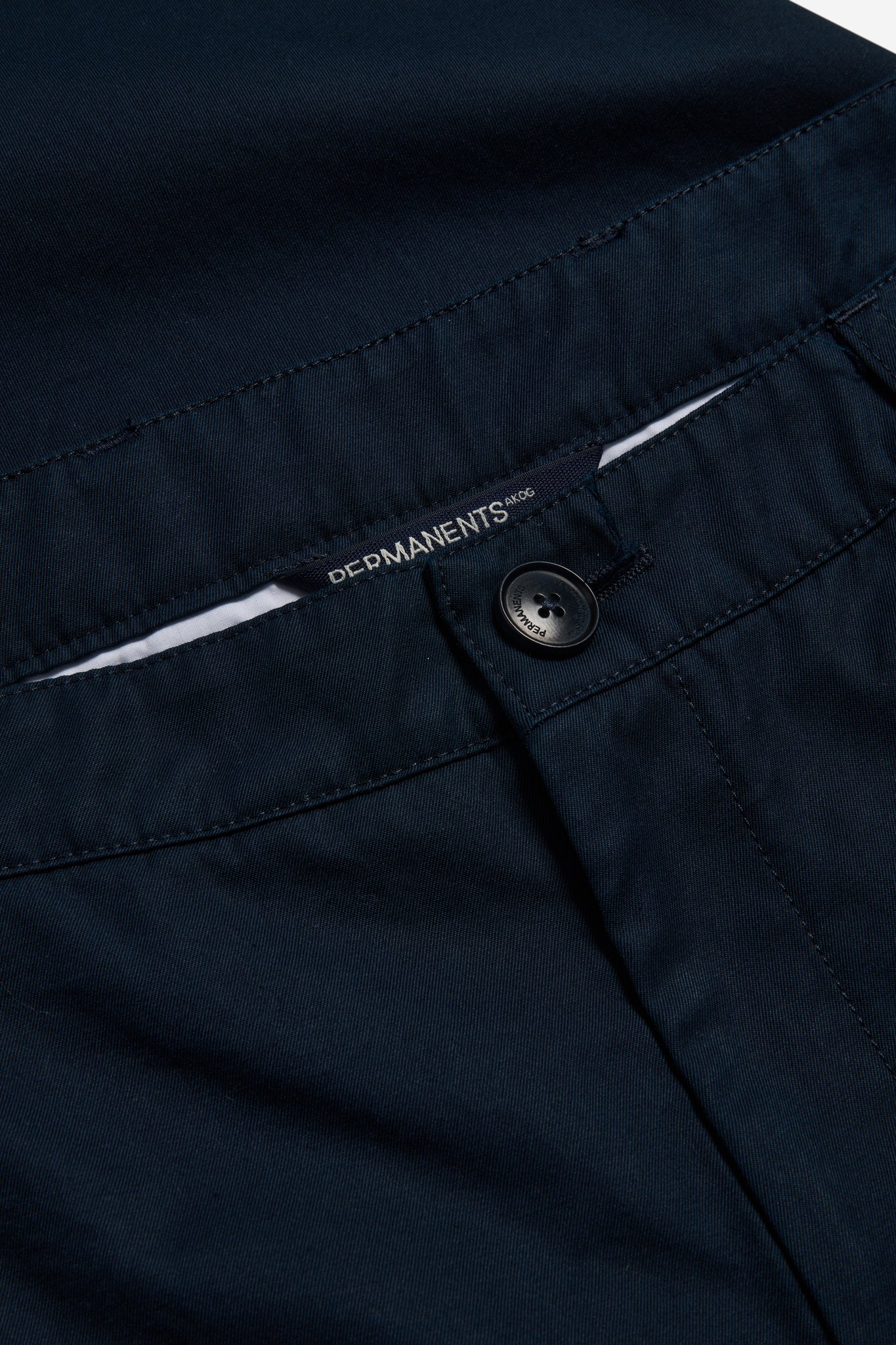 Men's long-pants, organic cotton twill, washed navy, with button closure and PERMANENTS® label.